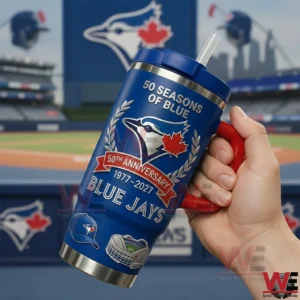 Hand holding a blue Toronto Blue Jays fiftieth anniversary tumbler with red handle and straw featuring the bird logo and anniversary text in a baseball stadium background!