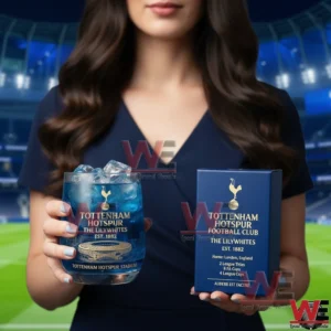 A close view of a blue Tottenham Hotspur themed glass with ice held by a woman in front of a football stadium background!