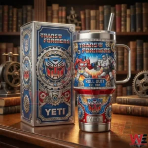 Transformers Roll Out insulated tumbler displayed next to a themed box on a wooden table with vintage mechanical decor in the background!