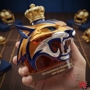 Hand holding a roaring wildcat head shaped bottle with blue gold details crown cap and championship text in a luxury sports themed setting!