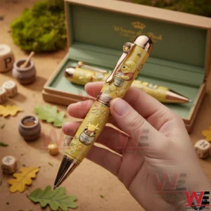 Hand holding a Winnie the Pooh themed pen with honey jar artwork and a matching wooden gift box in the background!