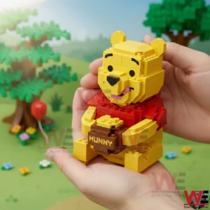 Hands holding a yellow brick bear figure with a honey pot in a colorful outdoor style setting!