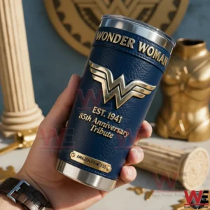 Hand holding a dark blue Wonder Woman insulated tumbler with anniversary tribute design in a themed setting!