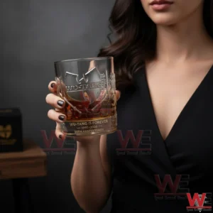 A female model displaying a Wu Tang Clan anniversary whiskey glass with iconic hip hop inspired artwork against a clean contemporary background!
