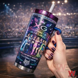 Hand holding an XG themed galaxy tumbler with purple lid straw and vibrant group design in front of a stage light background!