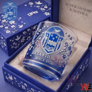 A clear whiskey glass with blue floral designs and a Zeta Phi Beta crest placed inside a matching blue gift box on a soft interior base!