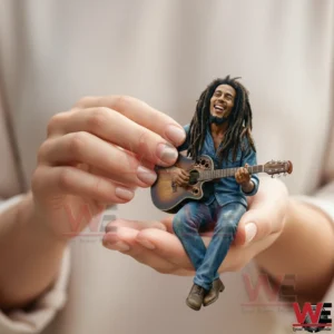 Small resin figurine of a smiling musician with long hair playing guitar while sitting in a human hand!