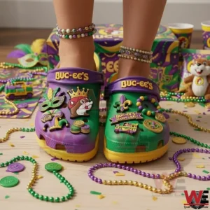 Person wearing Buc ee s Mardi Gras themed clogs with colorful carnival charms and beads on the floor.