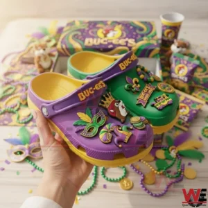 Hand holding Buc ee s Mardi Gras clogs with colorful charms in front of festive themed packaging.