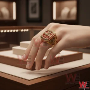 Gold and red Budweiser anniversary ring worn on a hand in a display case!