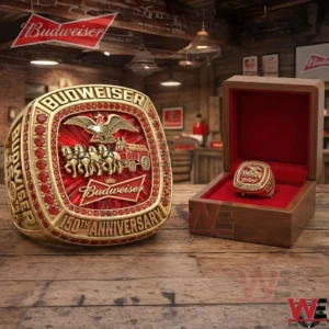 Gold and red Budweiser anniversary ring next to an open red lined box on a wooden table!