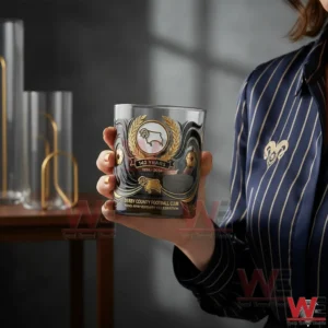 A hand holding a Derby County 142 years anniversary whisky glass with gold crest design!