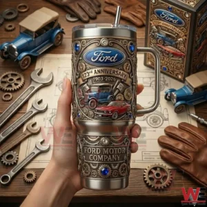 Ford 123rd Anniversary 1903-2026 Ford Motor Company Tumbler 5 Hand holding a Ford anniversary tumbler above a table with tools blueprints and vintage car models!
