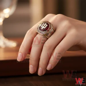 Hand wearing Indiana Hoosiers championship ring with red stone and IU logo.