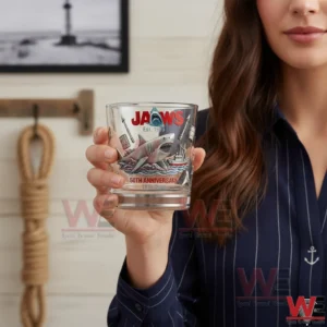 A person holding a JAWS themed whiskey glass with a shark illustration!