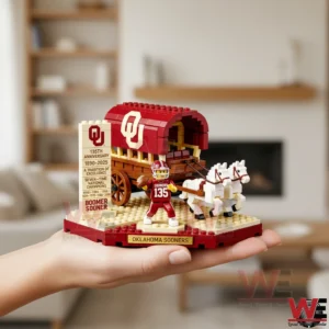 Hand holding Oklahoma Sooners 135th Anniversary brick wagon with football player and two white horses in living room.