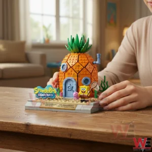 Spongebob 27th Anniversary 1999-2026 Building Brick set 3 Hands holding a brick built pineapple house display with a SpongeBob figure on a wooden table!