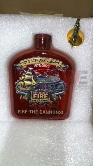 Commemorative red glass football themed bottle resting in foam packaging with a small decorative accessory!