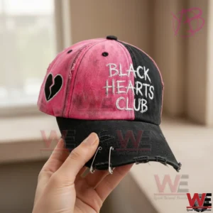 Pink and black Black Hearts Club baseball cap with broken heart patch and distressed brim.