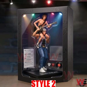 A high quality photo of a collectible AC DC figure set in its packaging! The matte black box has subtle lightning bolt designs and a transparent window! Inside is a detailed statue of Bon Scott carrying Angus Young with an SG guitar! Miniature colored lights are mounted inside the box! The stand says BACK IN BLACK! A small side compartment reveals a band pick and a vinyl record accessory! The box stands on a dark wooden table!