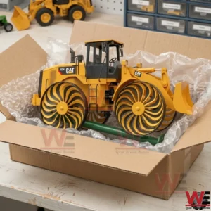 A yellow CAT construction model with unique wheels being prepared for shipping inside a cardboard box with bubble wrap.