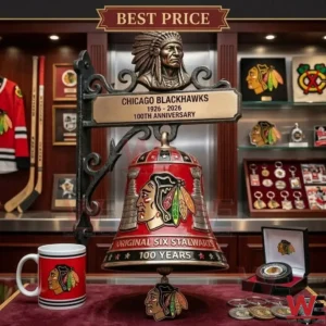 A professional photograph of a red Chicago Blackhawks 100 year anniversary bell! The bell features the team logo and Stanley Cup imagery! It is displayed with a mug puck and coins in a trophy room!