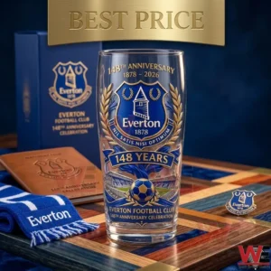 A celebratory Everton Football Club 148th anniversary glass is displayed on a wooden tray with a team scarf and notebook. The glass has blue and gold details including the team crest and a soccer ball. A gold banner is visible at the top.