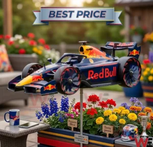 A Red Bull race car model is mounted on a stand over colorful flowers in a garden! A miniature helmet and trophy are displayed nearby on a wooden surface!