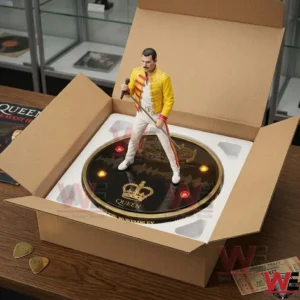 Freddie Mercury 80th Anniversary Glow Companion Lamp 7 A Freddie Mercury figure in a yellow jacket inside a shipping box with white foam! The base is lit up and features a gold crown! A concert ticket and guitar picks are on the table!