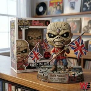 Iron Maiden Eddie collectible figure holding two Union Jack flags in front of its display box on a wooden shelf!
