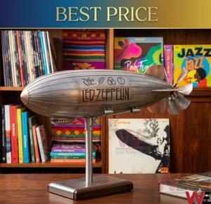 A silver Led Zeppelin airship model on a metal stand sits on a wooden desk! The background features a collection of vinyl records and books on wooden shelves!