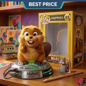 A collectible beaver figure with brown fur and a large tail on a metallic base with green lights! A nameplate on the base says Mabel Hoppers! Behind the figure is a yellow box and art supplies on a wooden table!