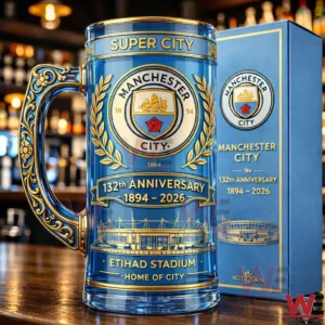 A decorative Manchester City anniversary mug on a wooden bar counter.
