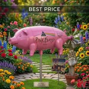 A pink Pink Floyd pig sculpture on a metal pole in a colorful flower garden! The pig has band logos on its side and sits near a stone hand statue and a miniature album cover!