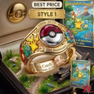A detailed gold Pokemon anniversary ring with character engravings sits in a box featuring grass and a small path!