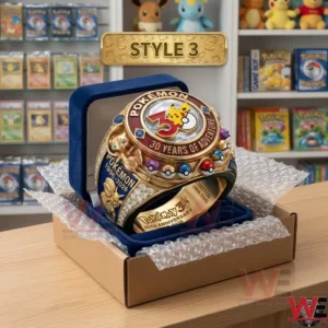 A gold Pokemon ring with red accents and character carvings sits in a blue velvet box inside a shipping carton!