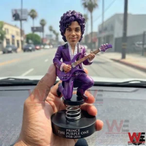 Purple musician bobblehead held over a car dashboard!