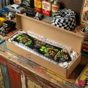 A Rat Fink necktie packed in a long cardboard box on a workbench with model cars and vintage garage items!