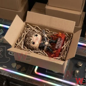 Brown haired vinyl figure in a cardboard box.