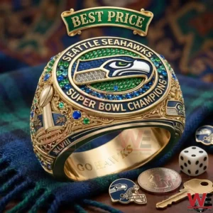 A gold ring encrusted with green and blue jewels and the Seahawks logo displayed on a plaid cloth!