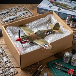 A finished airplane model in a shipping box on a workbench with paint jars and plastic parts!