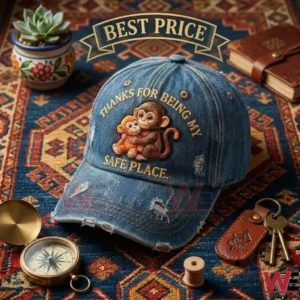 A distressed denim cap with monkey embroidery and sentimental text on a patterned rug with vintage accessories.