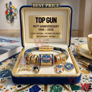 A Top Gun 40th Anniversary charm bracelet with gold fighter jet and helmet charms displayed in a blue velvet box on a table!