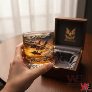 Hand holding a Top Gun themed glass with jet artwork beside an open wooden display box!