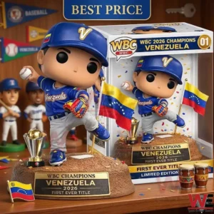 A photo shows two identical collectible figures of a Venezuelan baseball player in blue uniform and cap. One stands on a base with a plaque reading WBC CHAMPIONS VENEZUELA 2026 and a silver trophy. The other is inside its display box, which also has a large gold 01 and similar text. Small Venezuelan flags and bongo drums are on the shelf. The background is a wooden wall with pennants and a key.