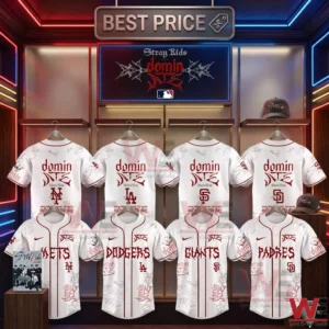 A store merchandise display photograph shows eight white Stray Kids baseball jackets with red trim hung in two rows in front of a wall with neon lighting! Jackets feature the dominATE album name and MLB team names written in artful script along with signatures! There is a large sign above with the group name and a hat in the back!
