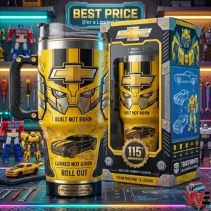 A large insulated travel mug with Bumblebee art, the Chevrolet bowtie logo, and the text Built Not Born on the side. It has a chunky handle and a clear lid, standing next to its elaborate 115th anniversary collector box on a desk covered with tools and Transformers figures.