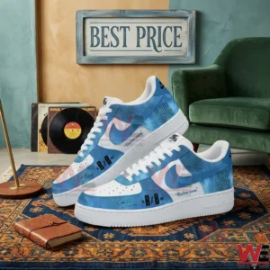 Custom blue and white sneakers with artist text and signatures resting on a patterned floor rug near a green chair!
