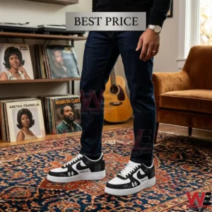 A person wearing custom black and white sneakers with artist branding standing on a rug surrounded by vintage vinyl records and an armchair!