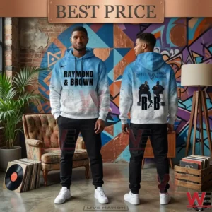 A single photograph of a black man modeling a light blue and white tie dye hoodie! He stands alone in an industrial loft with geometric wall murals painted on brick! The man faces the camera with his hands in his pockets wearing black joggers and white sneakers! The hoodie has bold black text Raymond and Brown and small handwritten details! A small picture inset in the corner shows the back design of the same tie dye hoodie!